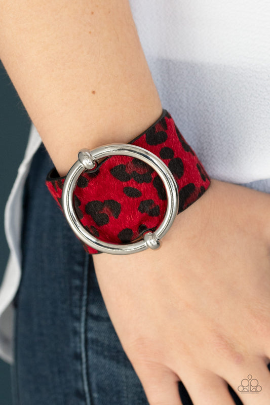 A dramatically oversized silver ring slides along a thick black leather band featuring fuzzy red cheetah print for a wild finish. Features an adjustable snap closure.

Sold as one individual bracelet.