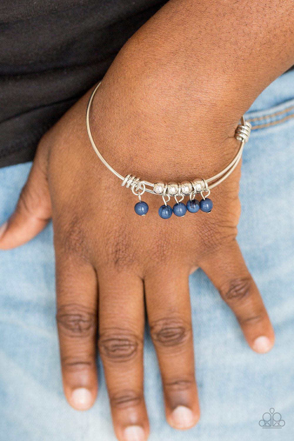 &lt;p&gt;Silver wire coils around the wrist, creating an adjustable-like bangle. Glassy blue beads slide between two wire wrap fittings, creating colorful accents along the wrist.&lt;/p&gt;
&lt;p&gt;&lt;i&gt;Sold as one individual bracelet.&lt;/i&gt;&lt;/p&gt;