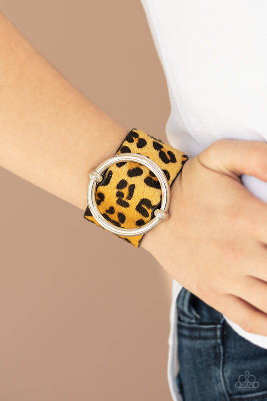 &lt;p&gt;A dramatically oversized silver ring slides along a thick black leather band featuring fuzzy yellow cheetah print for a wild finish. Features an adjustable snap closure.&lt;/p&gt;  

&lt;p&gt; &lt;i&gt;Sold as one individual bracelet.&lt;/i&gt;  &lt;/p&gt;


&lt;img src=\&quot;https://d9b54x484lq62.cloudfront.net/paparazzi/shopping/images/517_tag150x115_1.png\&quot; alt=\&quot;New Kit\&quot; align=\&quot;middle\&quot; height=\&quot;50\&quot; width=\&quot;50\&quot;&gt;